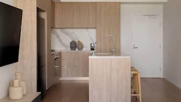 Una cocina moderna con armarios de madera, una isla integrada con un lavamanos y un televisor de pantalla plana montado en la pared.