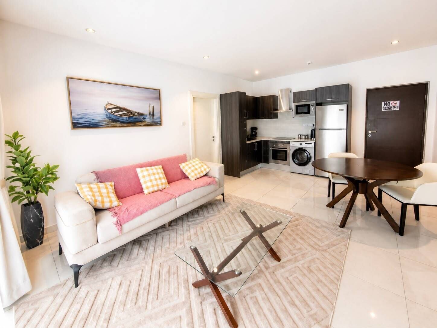 A modern living room with a sofa, a dining table, and a kitchen area with appliances.