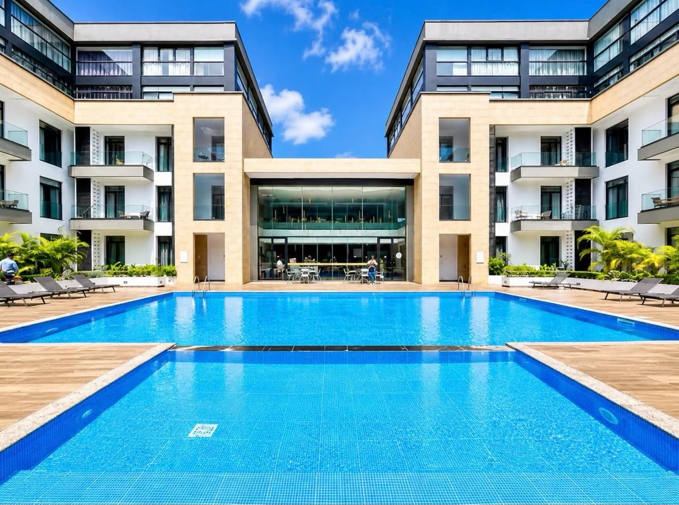 Een modern hotel met een centraal gelegen zwembad, meerdere balkons en een glazen gevel.