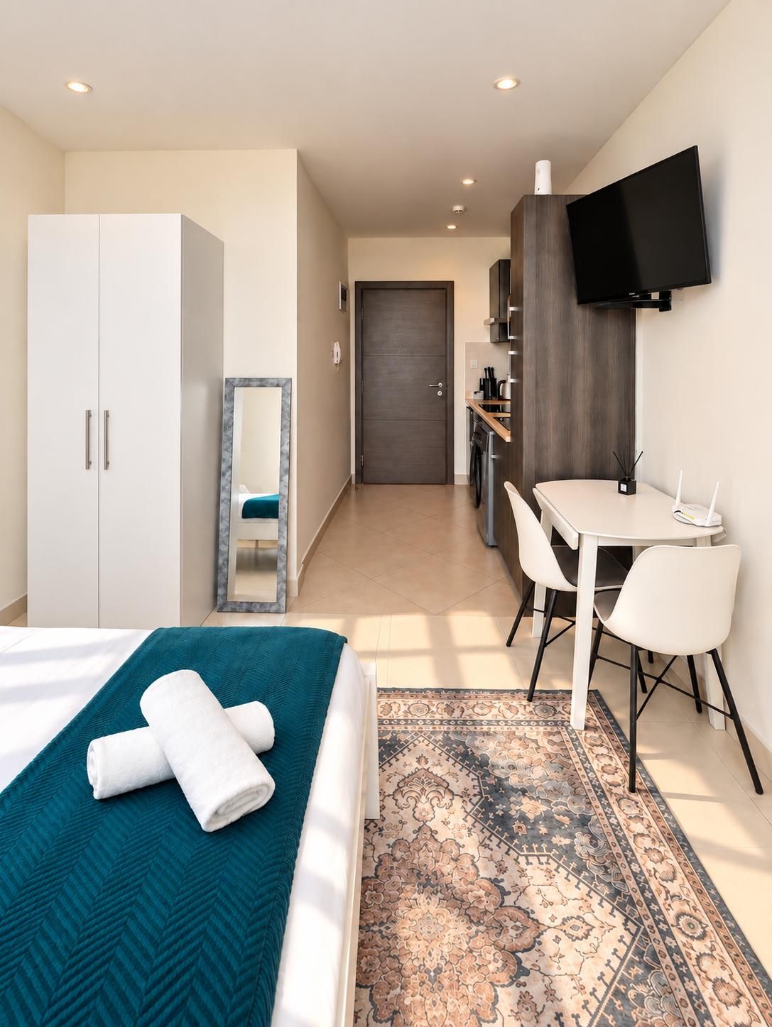 Una habitación de hotel con una cama, un escritorio, una silla, un televisor y un armario.