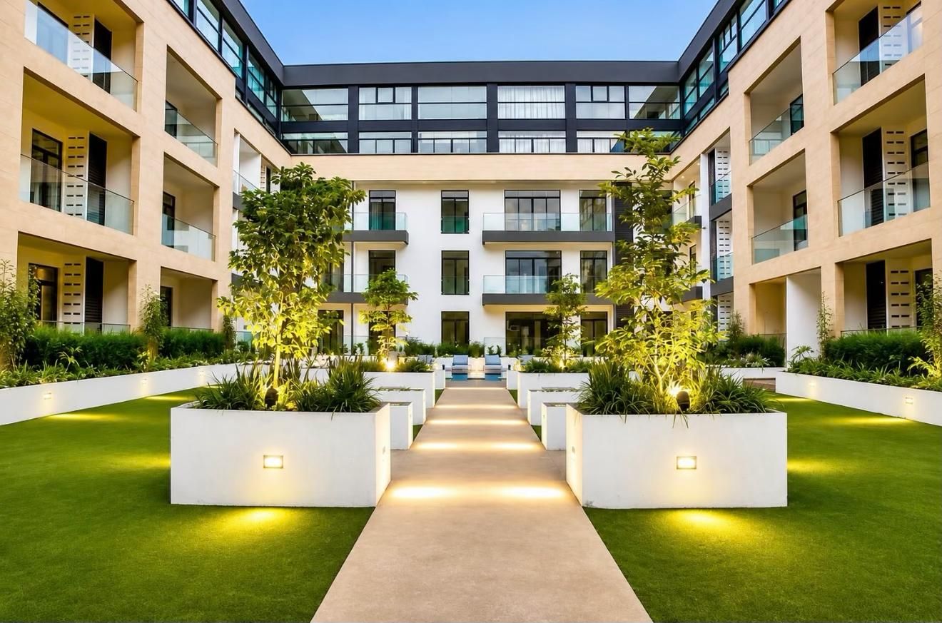 Un bâtiment moderne doté de nombreux balcons, d’une allée centrale et d’un espace vert bien entretenu.