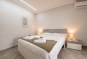 A bedroom with a bed, bedside lamps, a nightstand, an air conditioner, and a wall-mounted artwork. - Azores Green Escape (Povoação)
