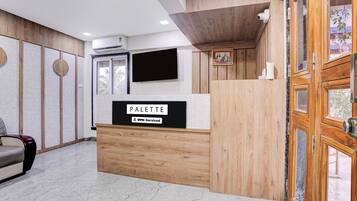 Un mostrador de recepción con un cartel que dice 'PALETTE' y un logotipo que indica OYO-Serviced.