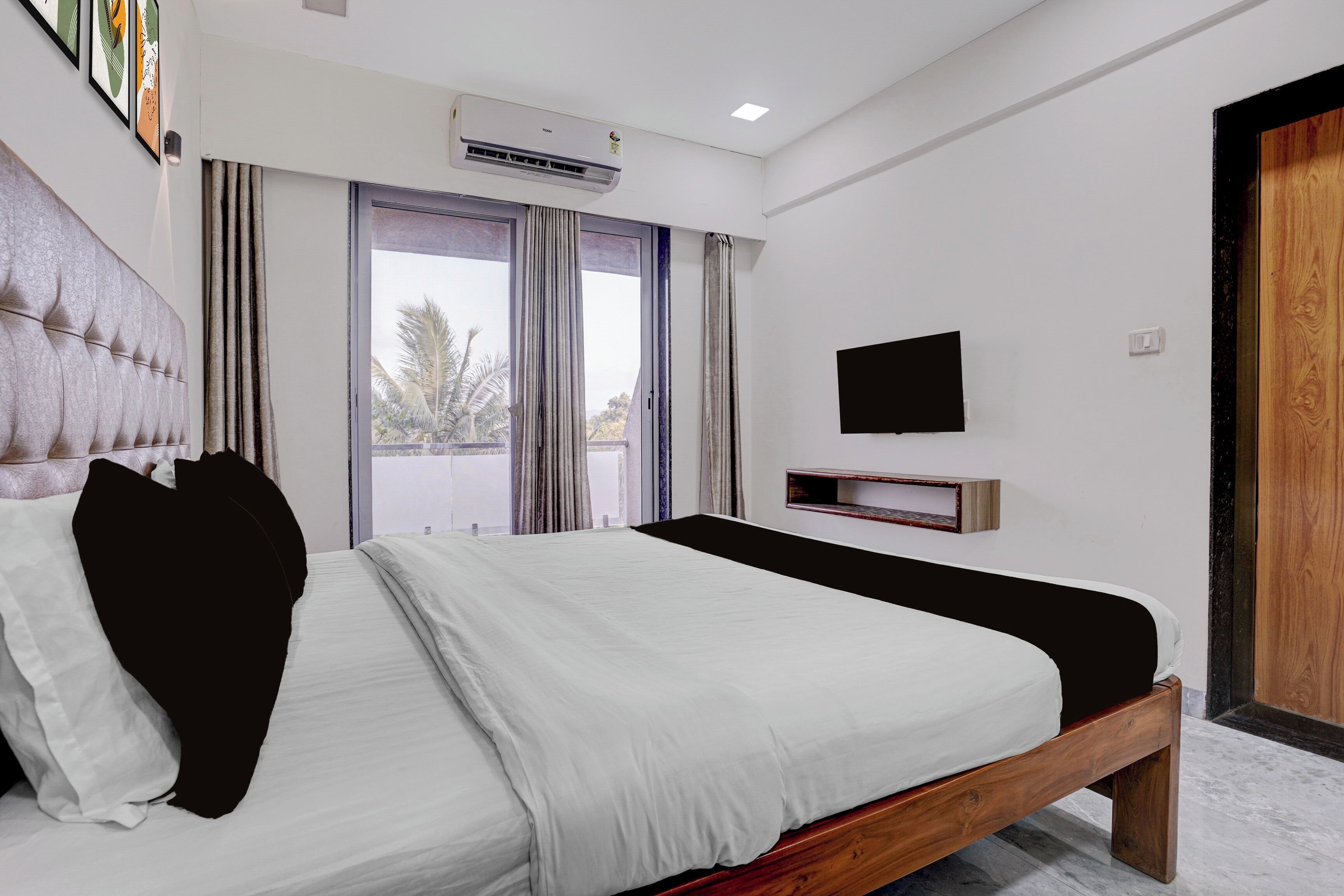 A modern bedroom with a large bed, an air conditioning unit, a television, and a sliding glass door.