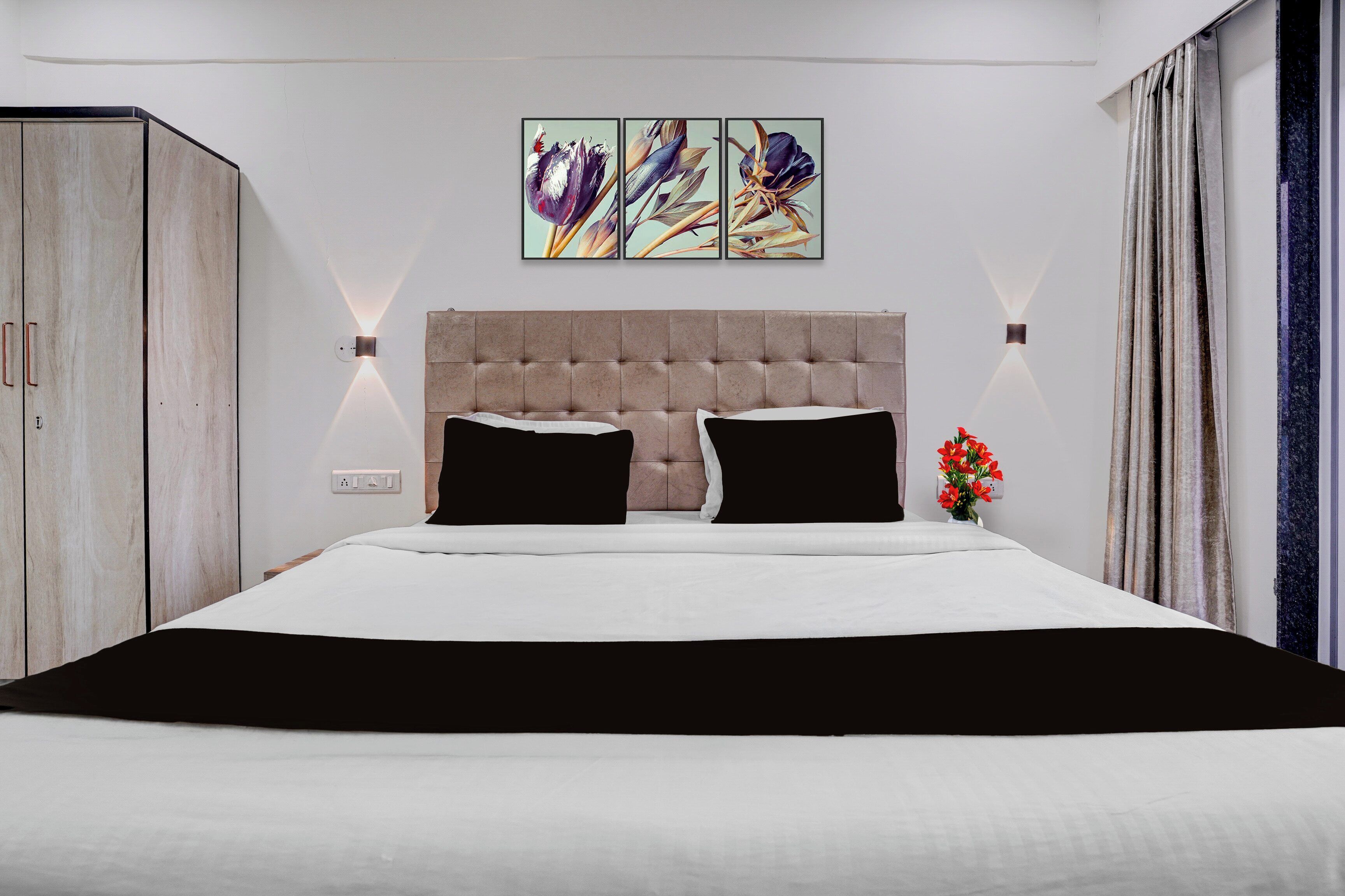 A bedroom with a large bed, a headboard, a wardrobe, and a wall-mounted light fixture.