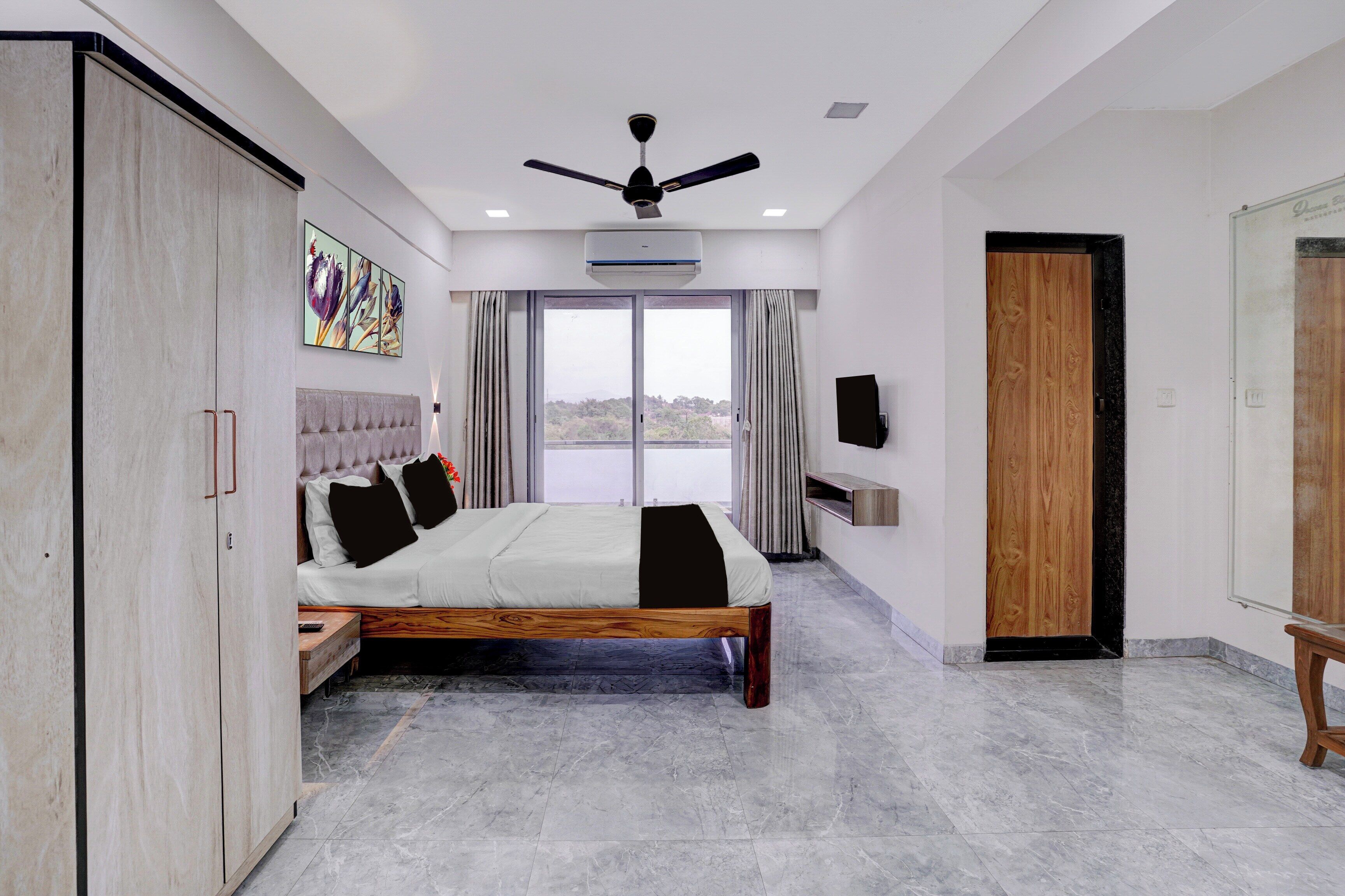 Une chambre à coucher comprenant un lit, une armoire, un ventilateur de plafond, un appareil de climatisation et une vue par la fenêtre.