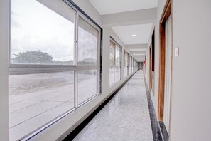 Un passadís llarg i estret amb grans finestres a un costat i portes a l'altre, que condueix a una habitació.