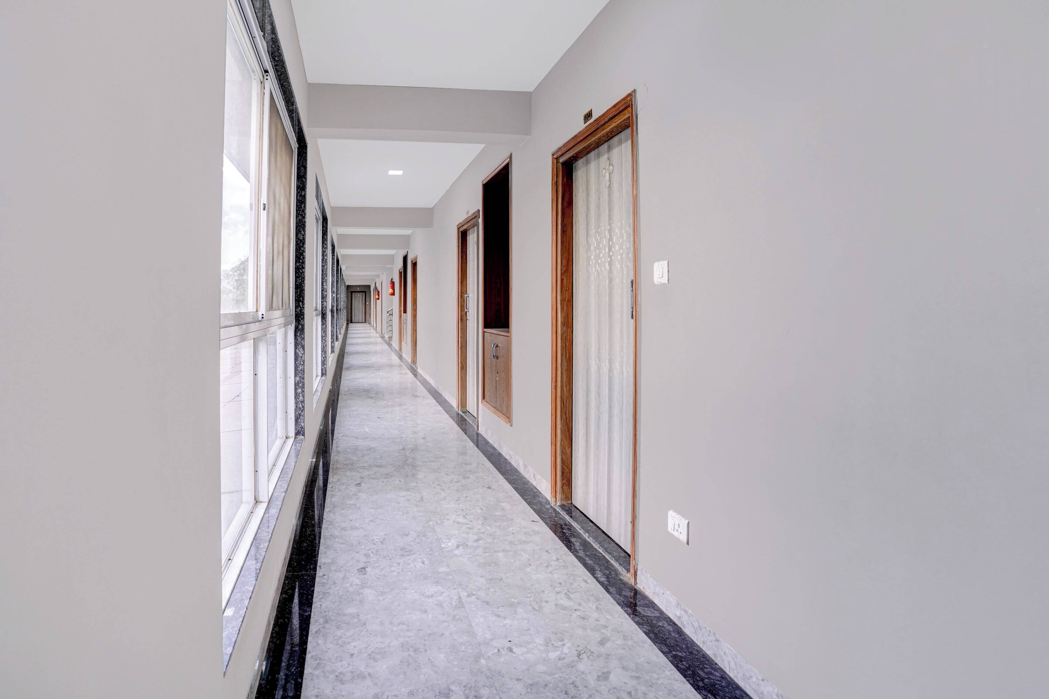 A corridor with doors on both sides, a marble floor, and a ceiling with recessed lighting.