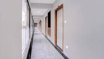 A corridor with doors on both sides, a marble floor, and a ceiling with recessed lighting.