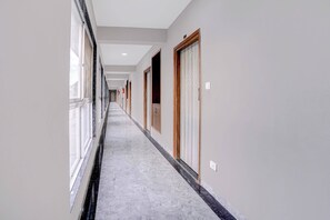 Un couloir bordé de portes des deux côtés, un sol en marbre et un plafond doté d’un éclairage encastré.