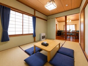 Ein traditioneller japanischer Raum mit Tatami-Böden, einem niedrigen Tisch und blauen Kissen.