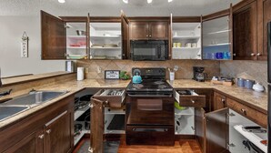 A kitchen with wooden cabinets, a microwave, a stove, and a sink. - Mountain Hearth - a RidgeView Resort Partner Property (Radium Hot Springs)