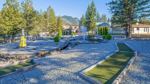 A golf course with a putting green, sand bunkers, and a water hazard. - Mountain Hearth - a RidgeView Resort Partner Property (Radium Hot Springs)