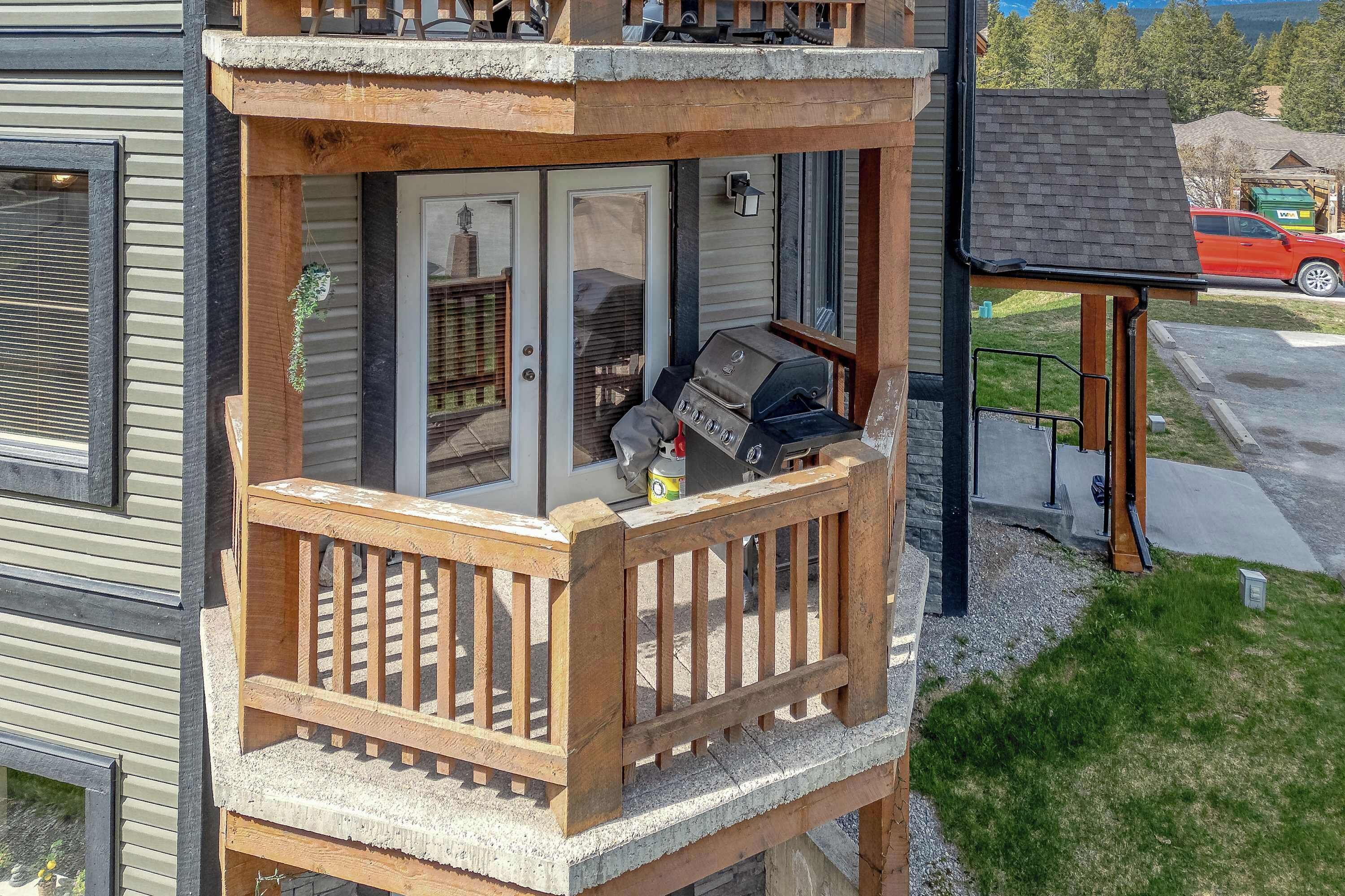 A wooden balcony with a grill, a door, and a small porch area.
