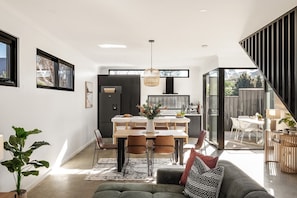 A modern kitchen with a dining area, large windows, and a staircase leading to an outdoor space. - Stone River Villa 4 | Serene Escape | Heated Pool (Margaret River)