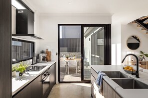 Een moderne keuken met een schuifdeur naar een terras met eettafel.