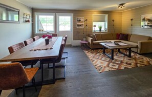 Ein Essbereich mit Holztisch, Stühlen und Teppich. Im Wohnbereich befindet sich eine Couch und ein Couchtisch.