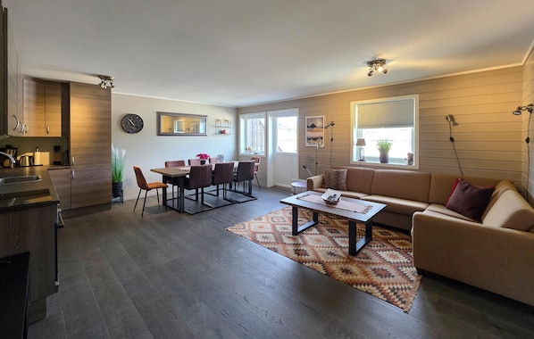 A modern living room with a dining area, wooden flooring, and a sofa.
