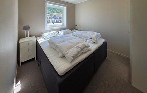 Ein Schlafzimmer mit einem Bett, einem Nachttisch, einer Lampe und einem Fenster.