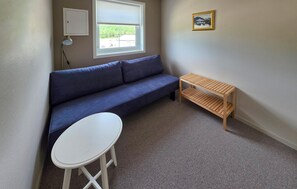 Une petite pièce avec un canapé bleu, une table blanche et un banc en bois.