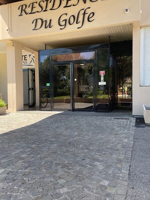 Ein Gebäudeeingang mit einer Drehtür, einem Schild mit der Aufschrift 'RESIDENCE DU Golfe' und einem Schild für Rollstuhlgerechtigtheit.