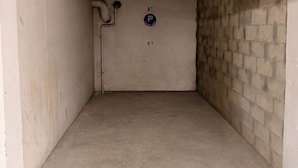 A vacant parking garage with concrete floors and walls, a blue parking sign, and a number '81' on the wall. - 06. Bright One-Bedroom Apartment with Terrace, Pool, Tennis Court and Garage (Vallauris)