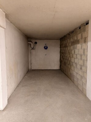 Eine leere Parkgarage mit Betonböden und -wänden, einem blauen Parkschild und der Zahl '81' an der Wand.