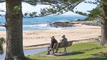A bench overlooking a beach with a view of the ocean.