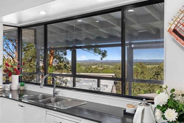 A kitchen with a large window, a sink, and a view of the outdoors.