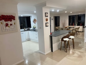 A modern kitchen with a central island, white cabinetry, and a dining area with bar stools.