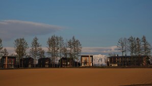 A row of modern cabins with a clear view of a mountain range in the background. - Adagio Retreat Tokachidake (Biei)
