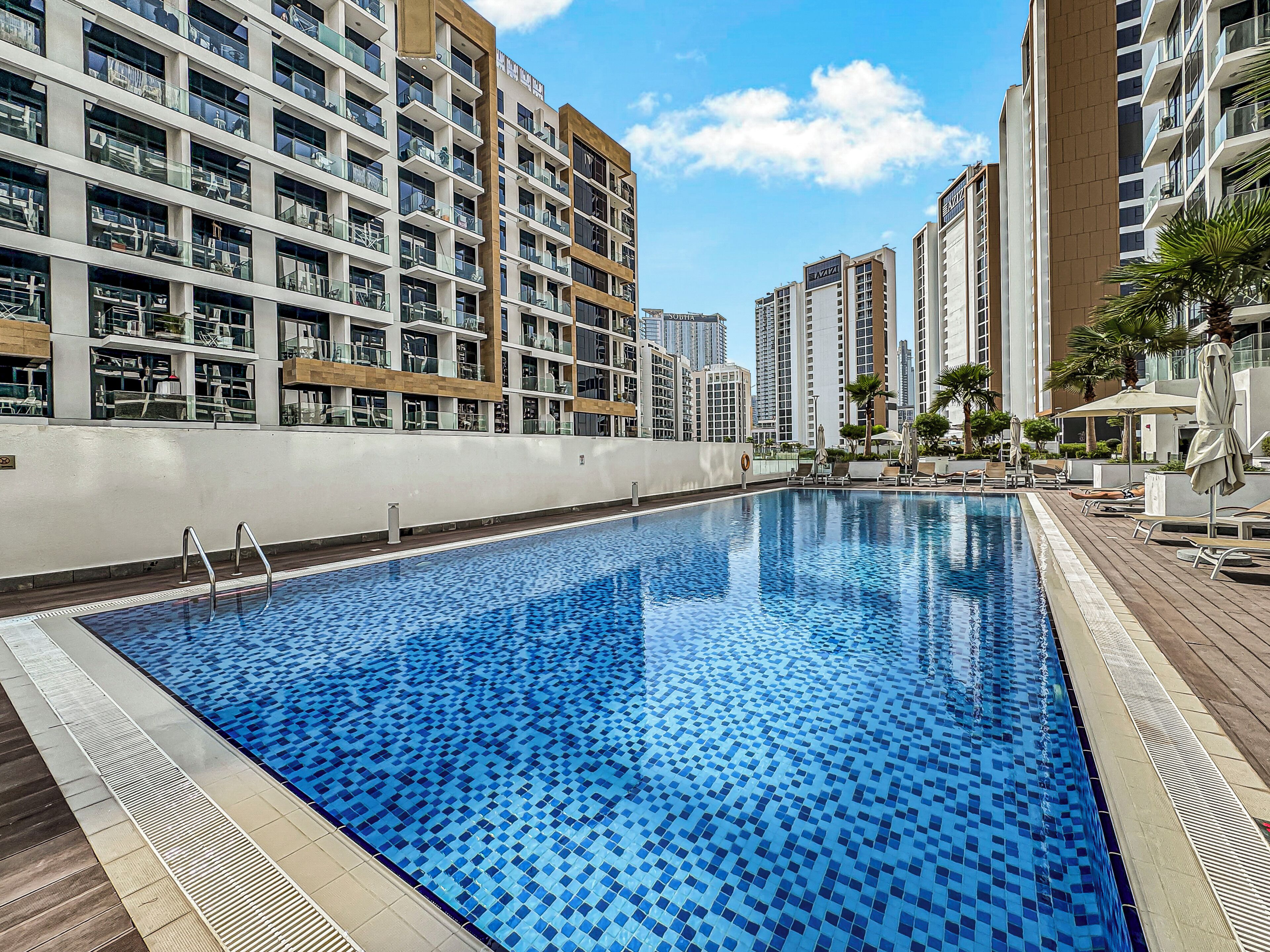 Una piscina con borde de azulejos, rodeada de edificios residenciales altos.