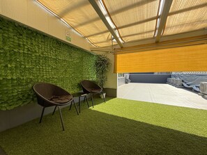 An indoor space with artificial grass, wicker furniture, and a wall covered in green foliage. - OSAKA-03 (Osaka)
