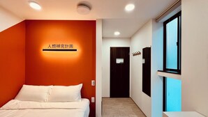 Quarto de hotel com cama, placa na parede, janela e porta.
