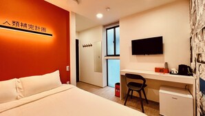 Quarto de hotel com cama, escrivaninha com cadeira, televisão e cafeteira.