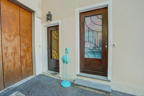Un pasillo con dos puertas de madera, una con ventanal y la otra con timbre.