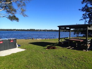 A lakeside area with a gazebo, picnic tables, and a grill. - Dungowan Holiday Accomodation (Sanctuary Point)