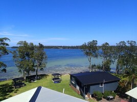 A lakeside property with a house, a covered outdoor seating area, and a boat dock.