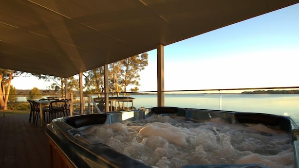 Ein Whirlpool mit Seeblick, Sitzgelegenheiten im Freien und eine überdachte Terrasse.
