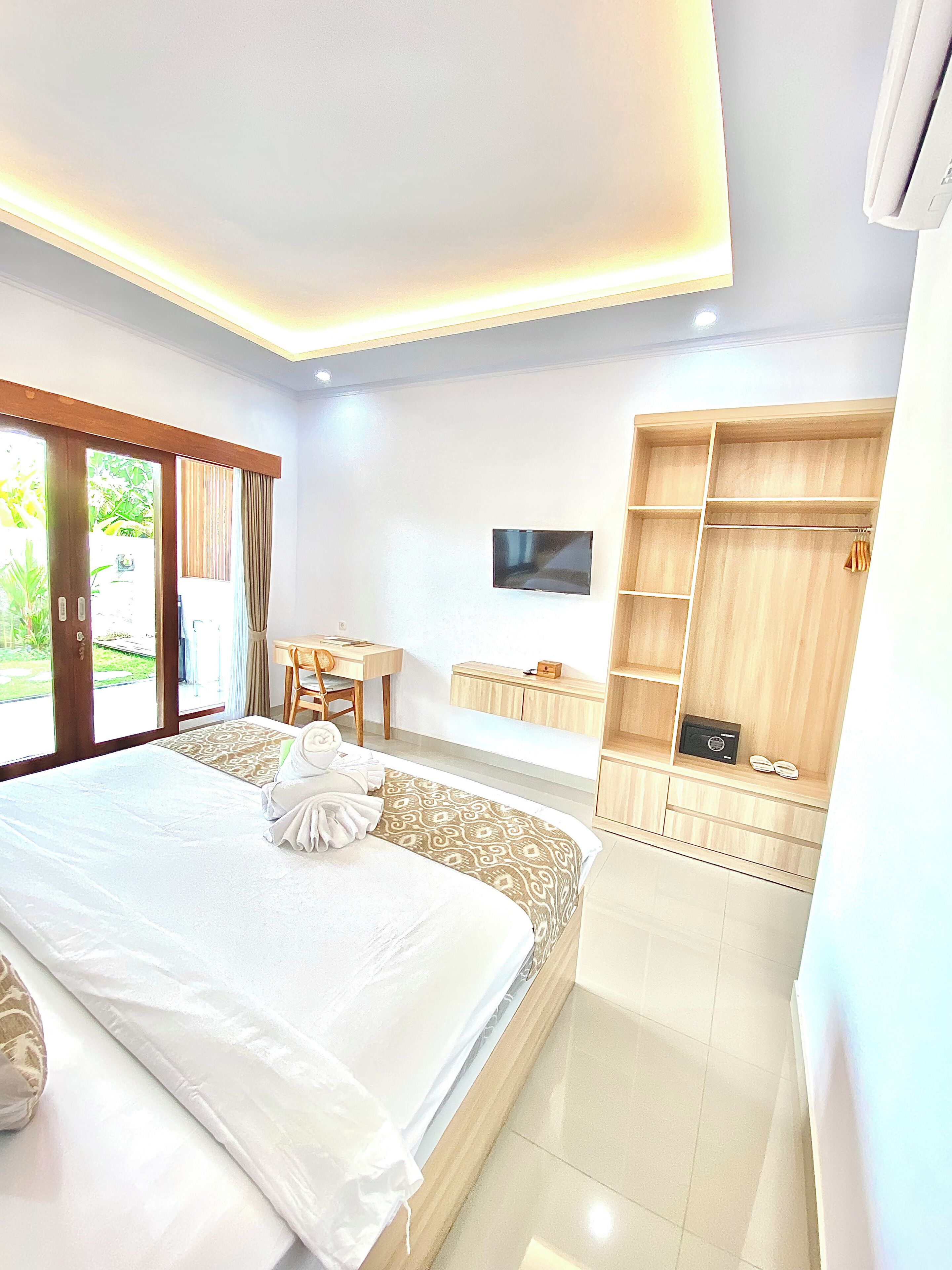 A hotel room with a large bed, a desk, a TV, and a wardrobe.