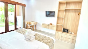 A hotel room with a large bed, a desk, a TV, and a wardrobe. - Desri Ubud (Ubud)
