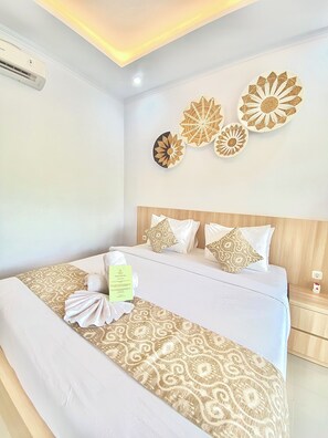 Een hotelkamer met een bed, nachtkastje en wanddecoraties.