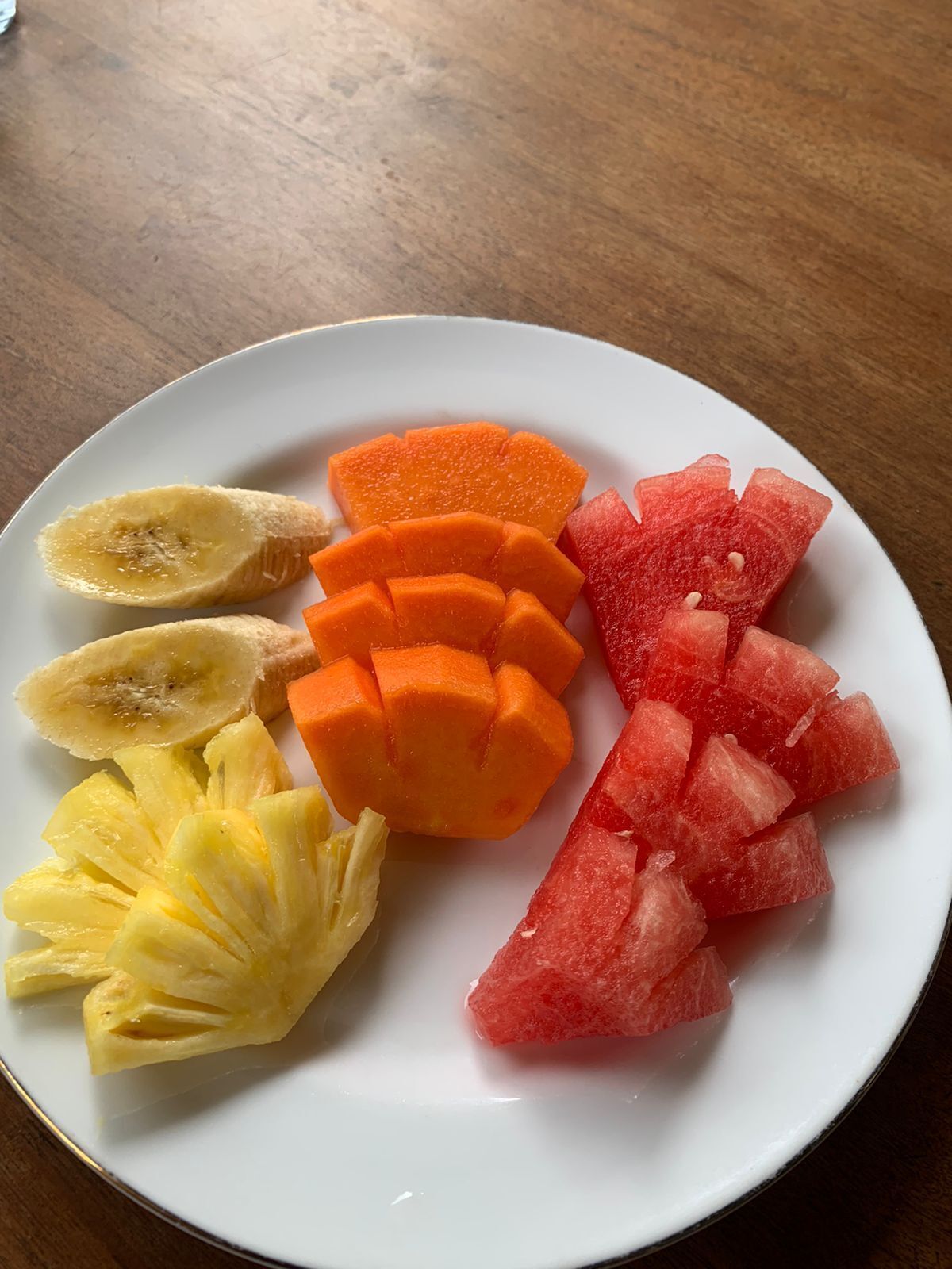 Un plato con frutas cortadas como piña, mango y sandía.