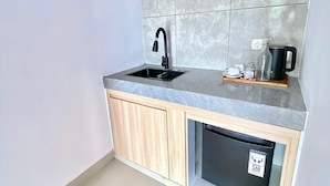 A compact kitchen with a built-in dishwasher, a black faucet, and a coffee maker on the countertop. - Desri Ubud (Ubud)