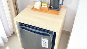 A compact kitchenette with a coffee maker, kettle, and a bottle on a wooden tray. - Desri Ubud (Ubud)