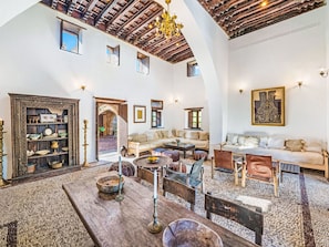 An interior with a high arched ceiling, a wooden table, a sofa set, and a decorative cabinet. - Vasilikos Mansion by Interhome (Pefki)