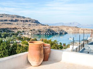 A coastal landscape with terracotta pots on a balcony overlooking a calm bay with boats, rocky hills, and distant mountains. - Vasilikos Mansion by Interhome (Pefki)
