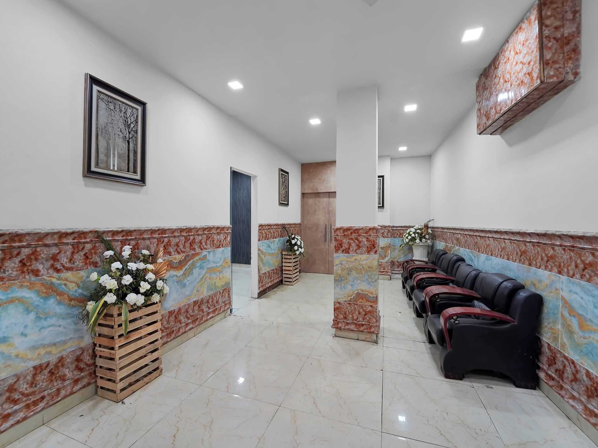 A hallway with a marble wall, a wooden bench, and a row of massage chairs.