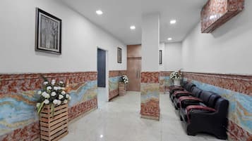 A hallway with a marble wall, a wooden bench, and a row of massage chairs.