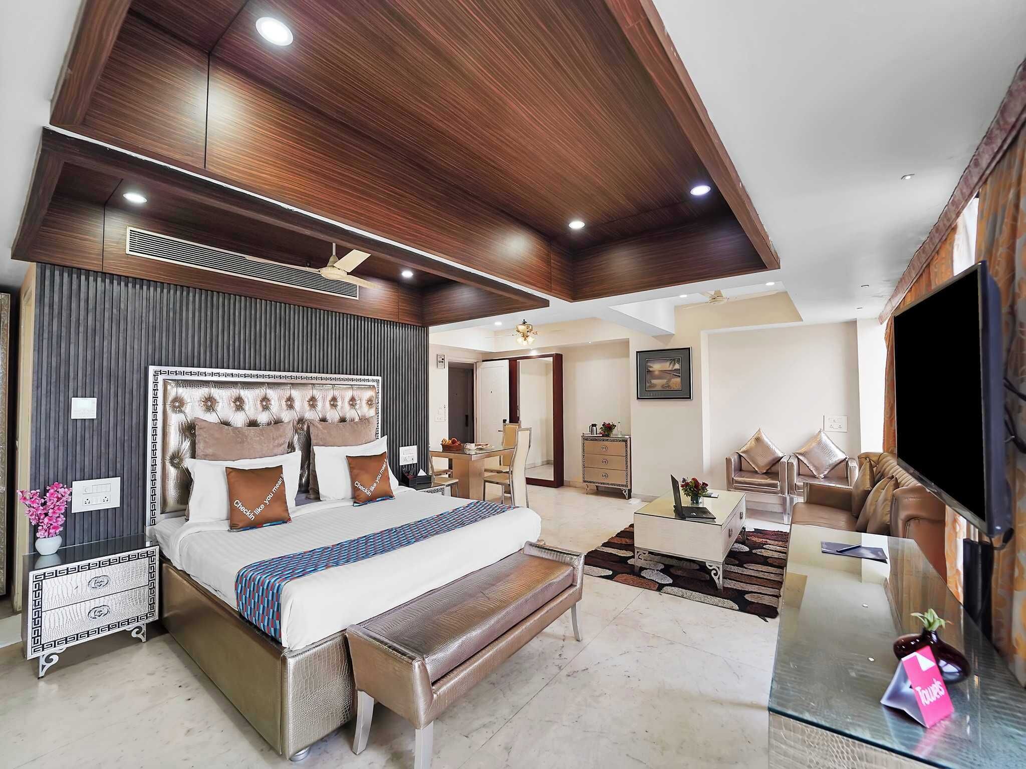 Quarto moderno com cama grande, escrivaninha, sofá e televisão.